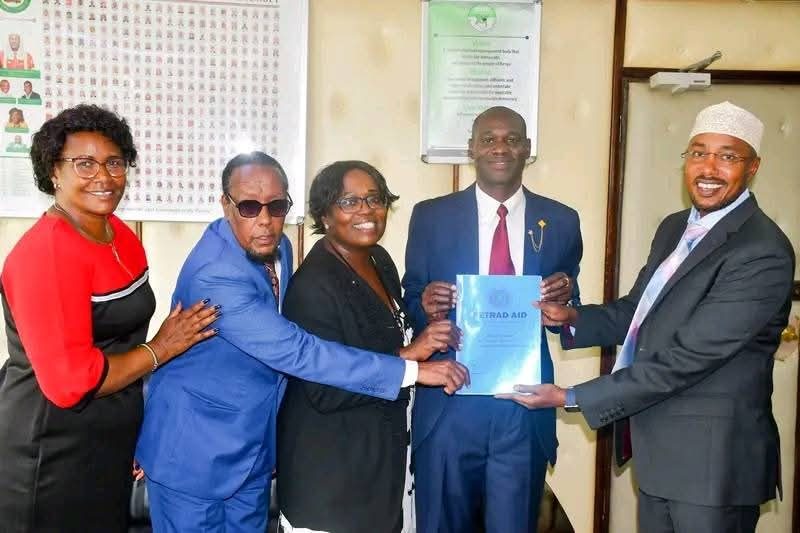 PETRAD AID leadership presenting document to senior government official — IEBC partnership engagement