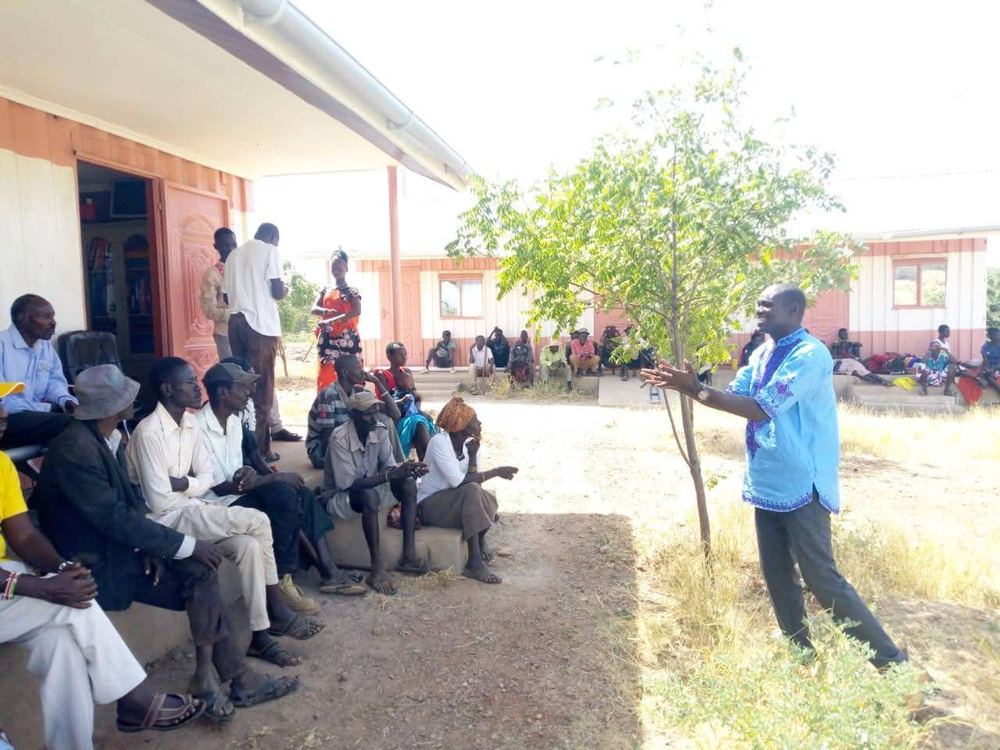 PETRAD AID peace facilitator addressing community members outdoors — Kakuma